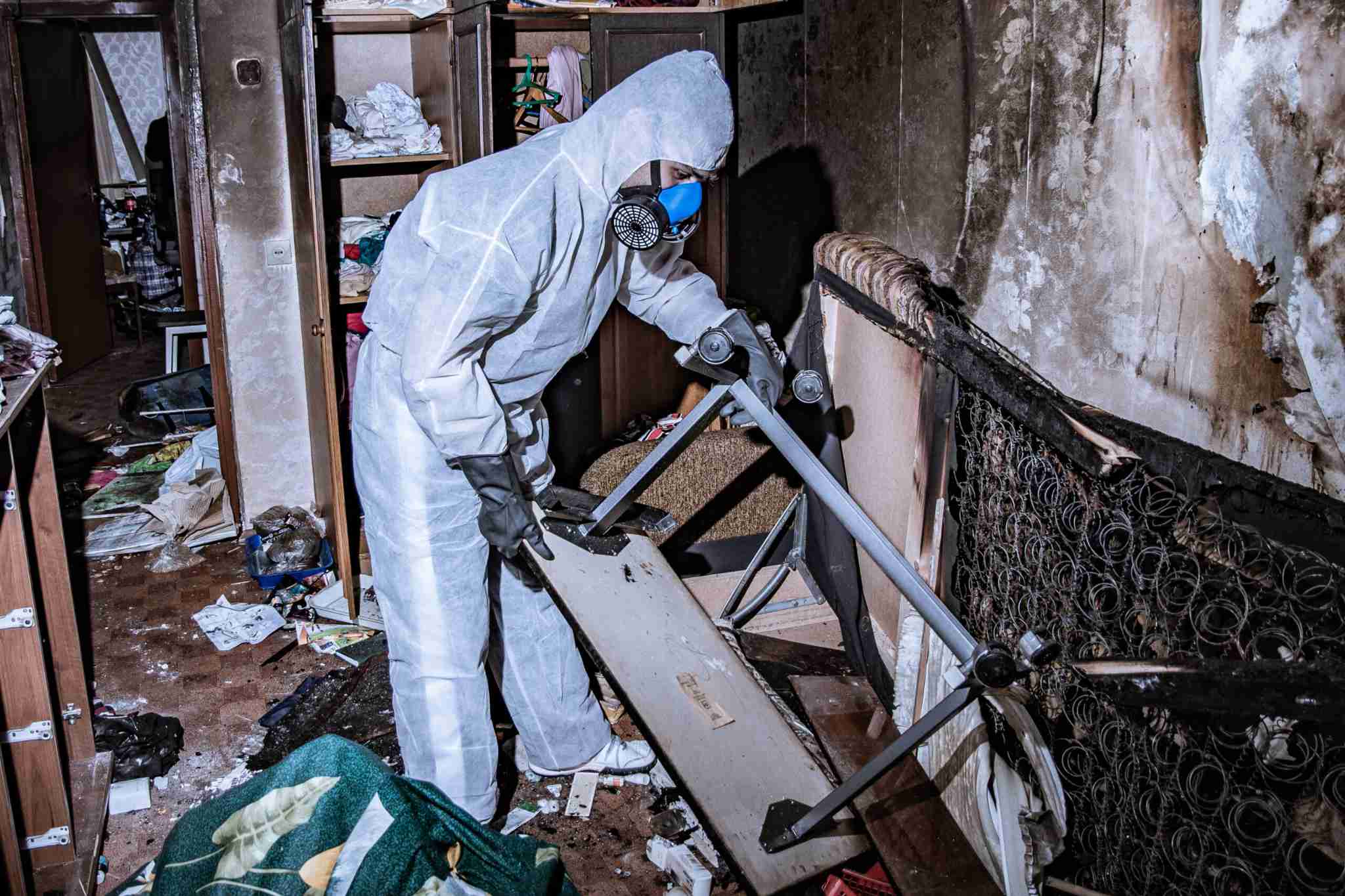 Technician in protective gear removing fire-damaged furniture and debris during smoke and fire damage restoration service in Staten Island, NY