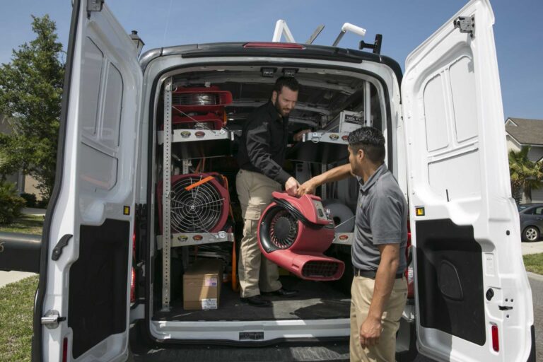 Paul Davis Restoration technicians unloading air movers and drying equipment from service van for water damage restoration in Staten Island, NY